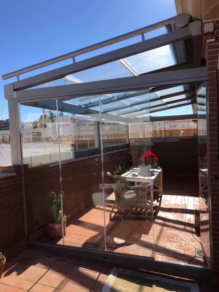 Cerramiento de cristal en terraza con mesa y sillas de exterior